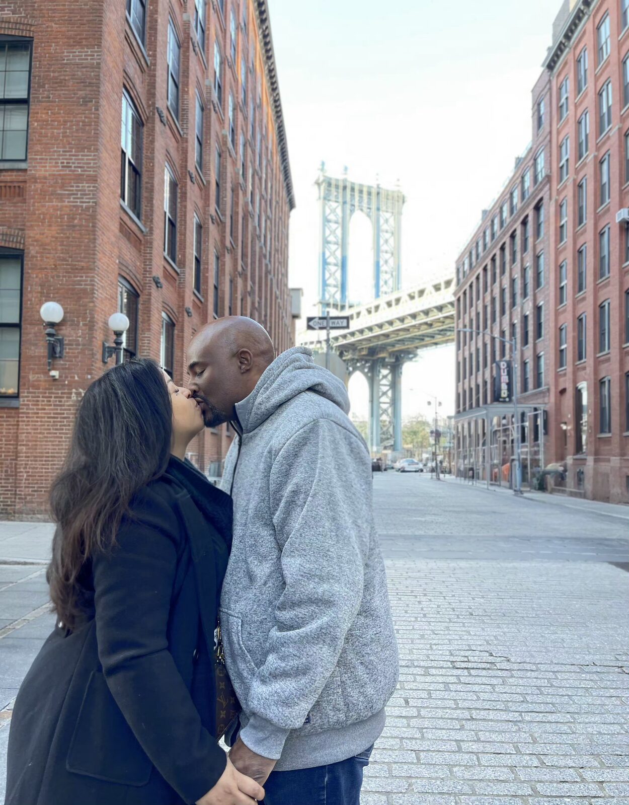 Sabina and her husband kissing on Washington Street in DUMBO, the Manhattan Bridge framed behind them