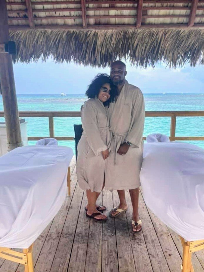 Sabina and her husband in matching spa robes on the deck of an overwater cabana