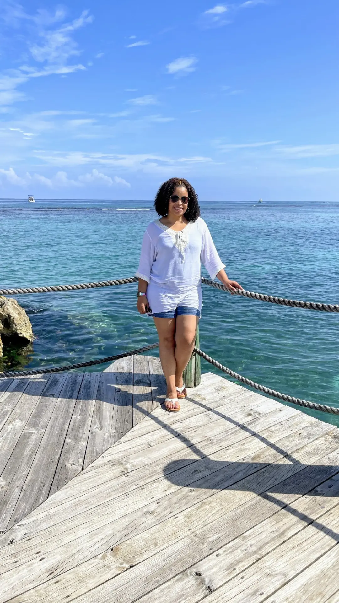 Sabina Long standing alone on a weathered wooden pier over turquoise water